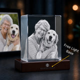 A personalized acrylic photo cube on a dark wooden base, displaying a black-and-white portrait of a woman and her golden retriever. The base is engraved with the 'SOLID CRYSTALS' brand name and features a yellow callout line pointing to it with the text 'Free Light Base'.